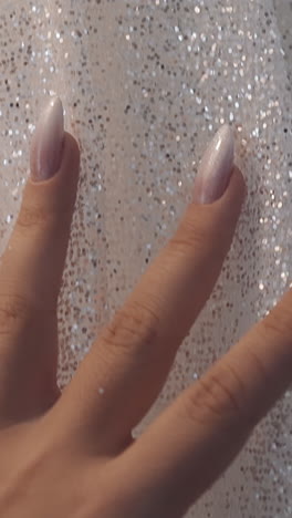 woman hand touches elegant wedding dress with glitter decor in salon closeup slow motion. fashion and marriage ceremony. life event holiday