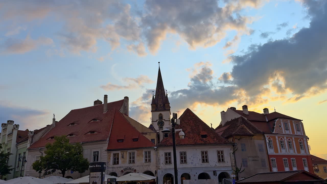 Sibiu, Romania, 17 July 2025: Sibiu old town at sunset. Colorful houses with church spire and dramatic sunset clouds in Sibiu, Romania