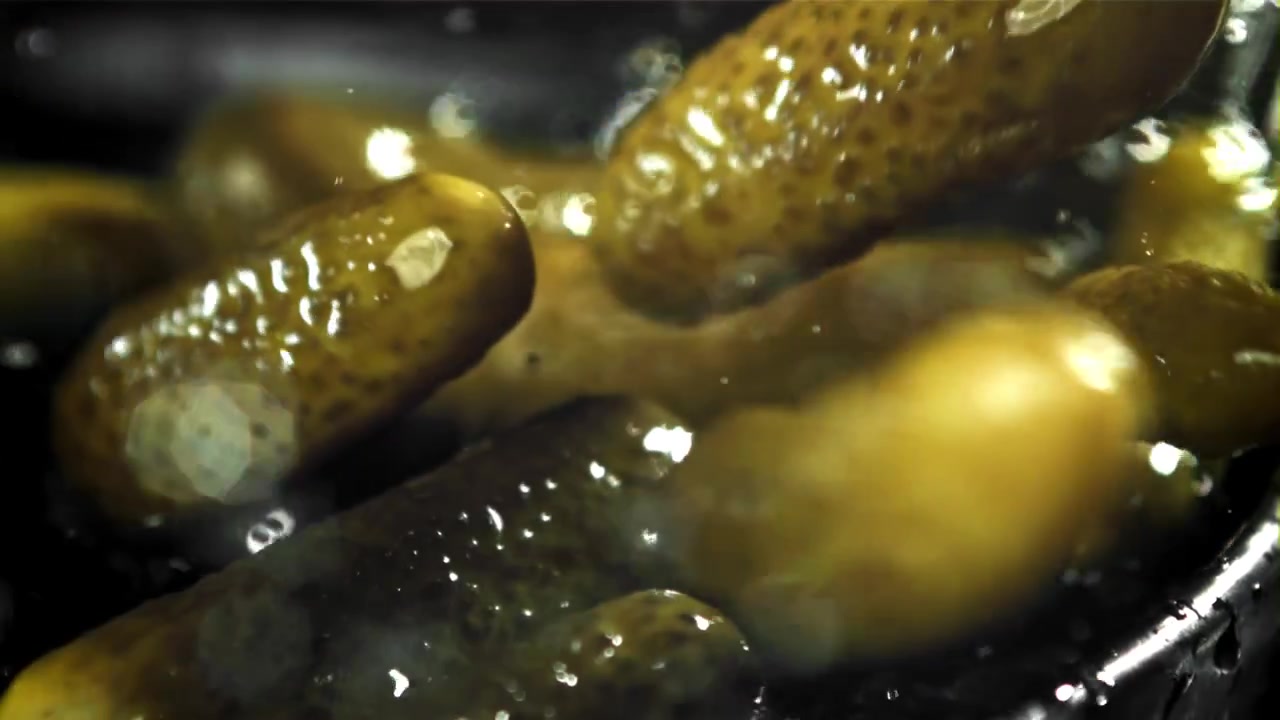 Ferske sylteagurker som plasker ned i vann i sakte film