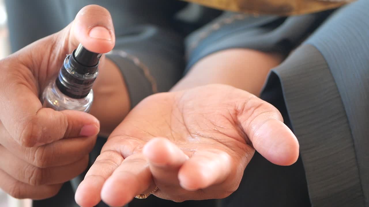 여성이 향수 또는 손 소독제를 사용하고 있습니다.