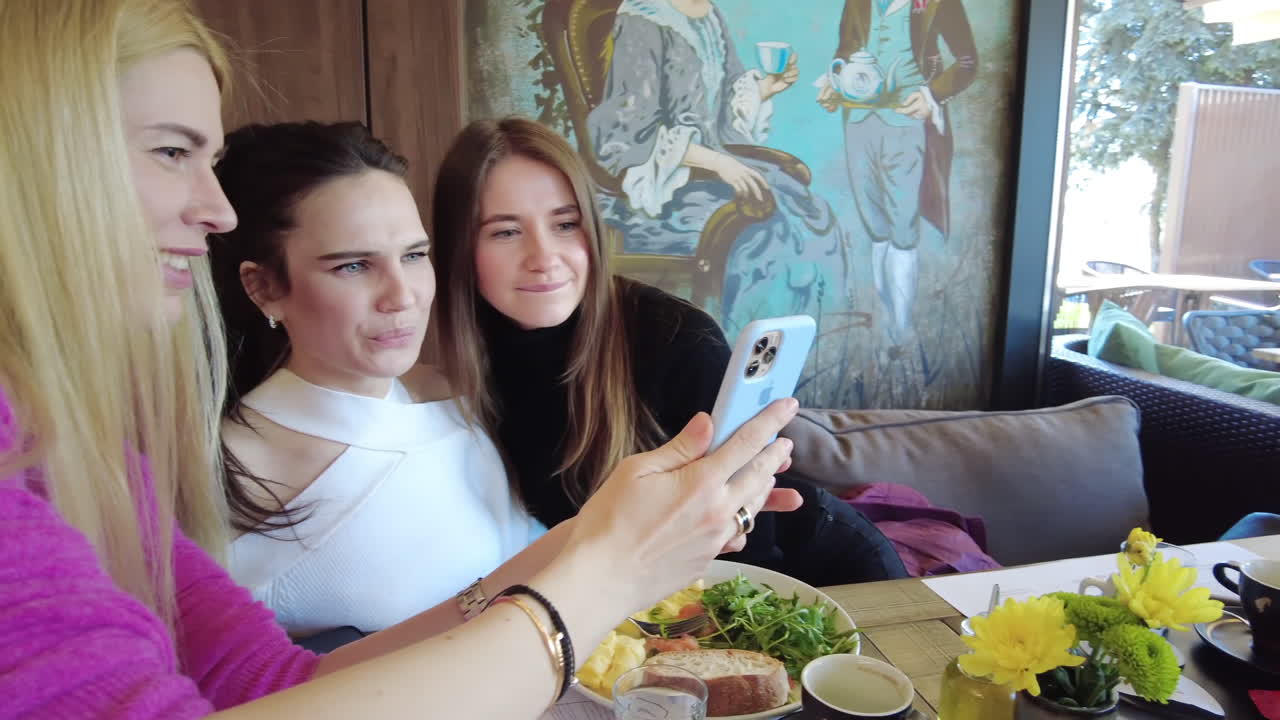 Three women looking at pictures at a phone at a restaurant