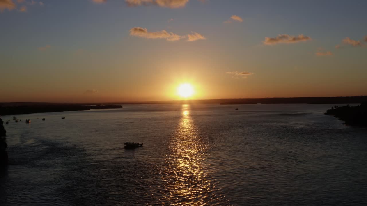 Aerial drone wide shot of the huge tropical Guara&iacute;ras Lagoon with a ferry boat in the famous beach town of Tibau do Sul during a golden colorful sunset near Pipa Brazil in Rio Grande do Norte