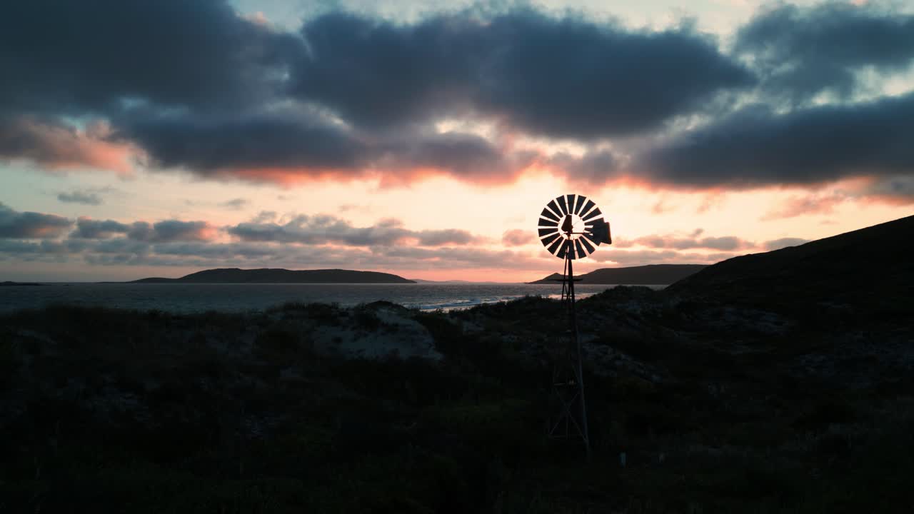 drone neergeschoten over twilight beach bij zonsondergang vliegend dicht bij een windmolen, esperance, west-australië