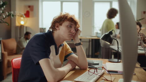 timelapse of apathetic young man sitting at desk, looking at computer in office