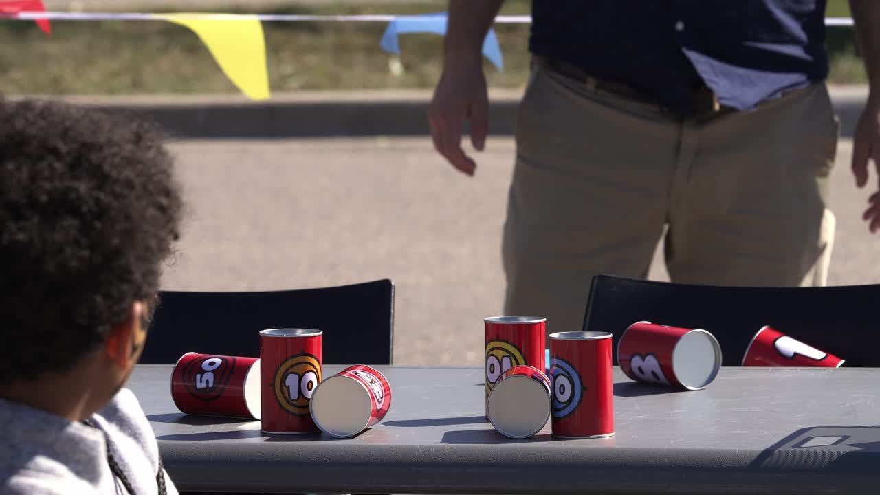 Bambini che lanciano sacchetti di fagioli contro lattine al rallentatore