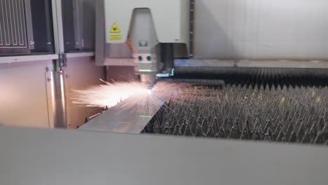 industrial laser cuts a metal sheet and sparks fly