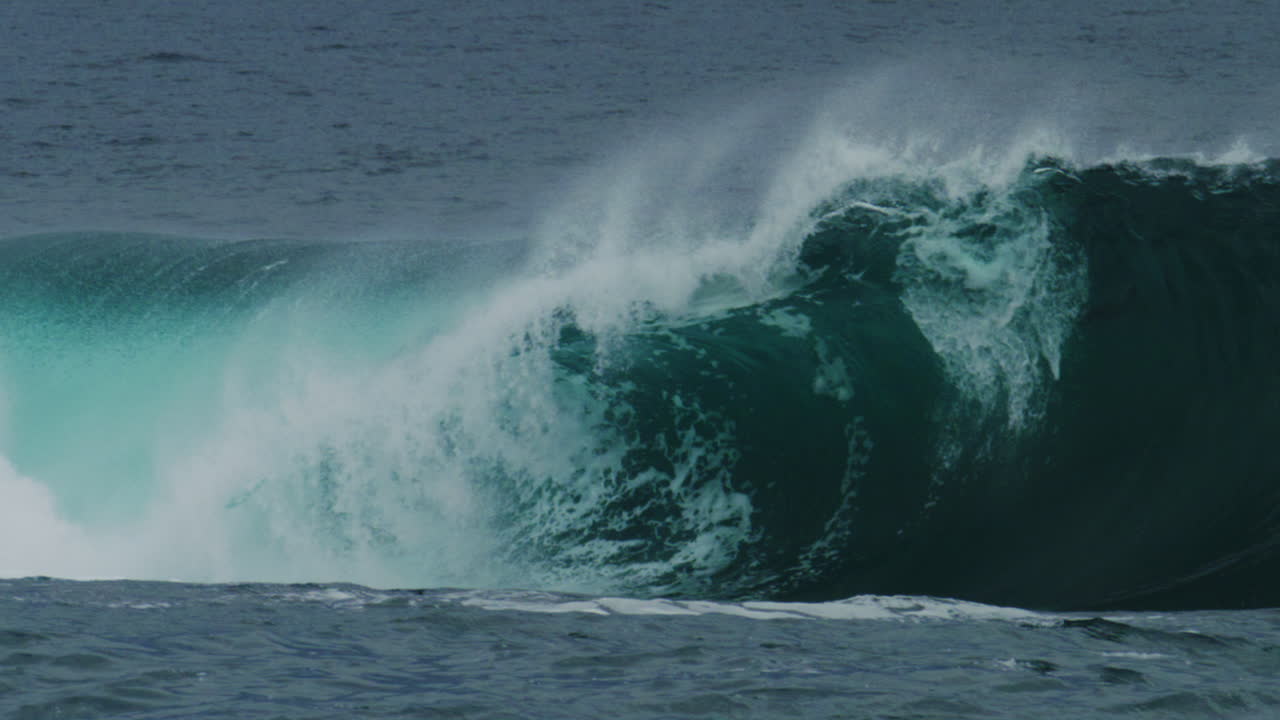 Telephoto close-up of rising wave wall as light passes through lip and spray shoots skyward
