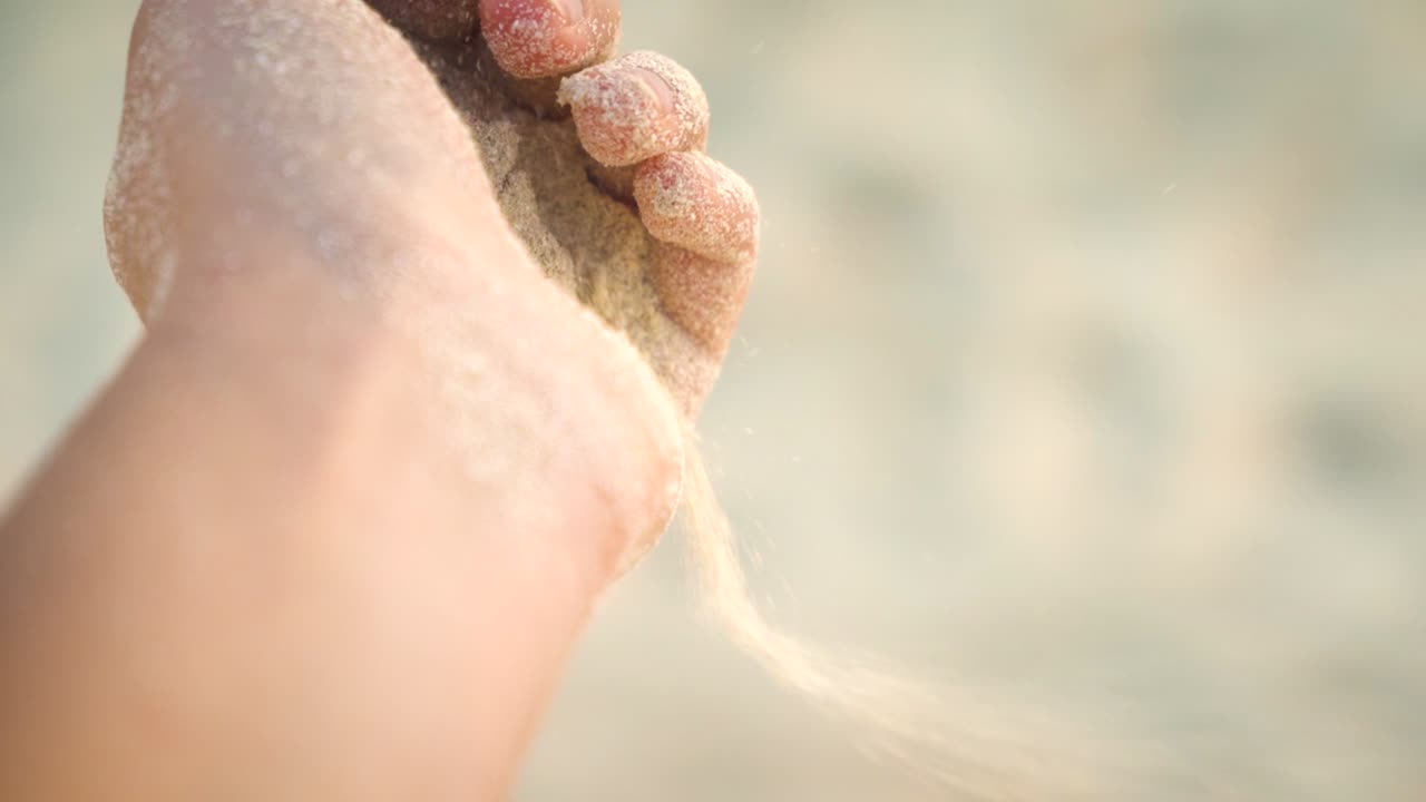 Close view of sand that pours away through the woman fingers at the carribean beach