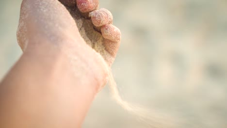 close view of sand that pours away through the woman fingers at the carribean beach