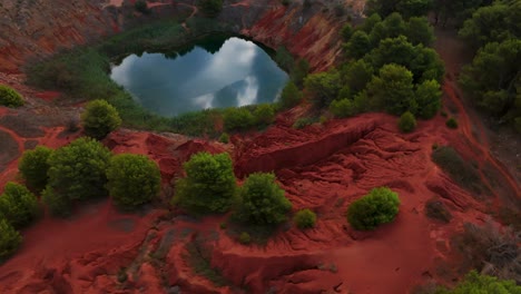 otranto, puglia, italy - a stunning view of the bauxite cave, with the lake reflecting the overcast sky - orbit drone shot