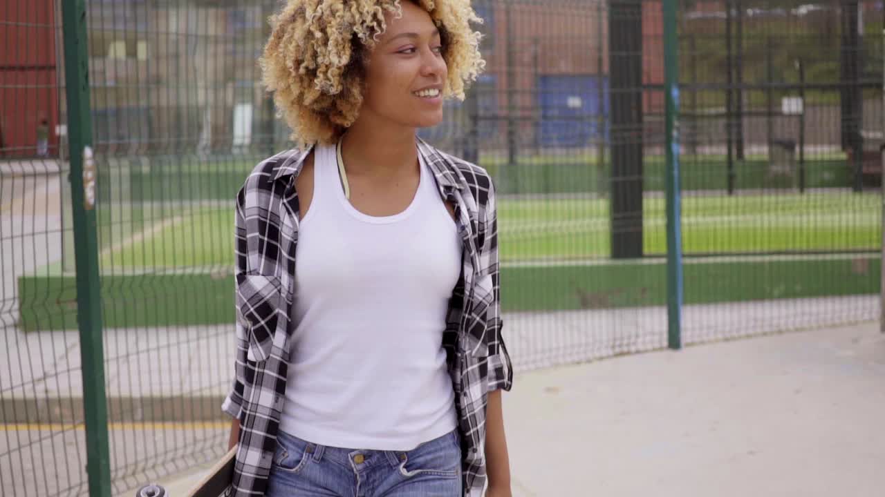 Ragazza attraente che cammina con lo skateboard