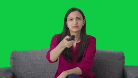 mujer india tratando de arreglar la pantalla verde remota de la tv