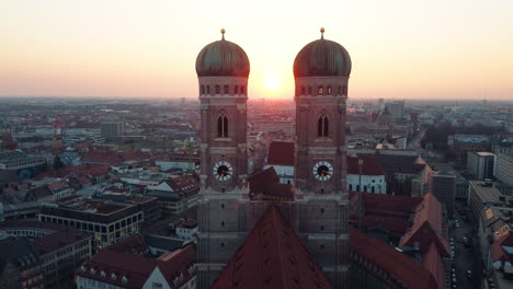 aerial backwards shot showing silhouette of frauenkirche towers at golden sunset in munich city