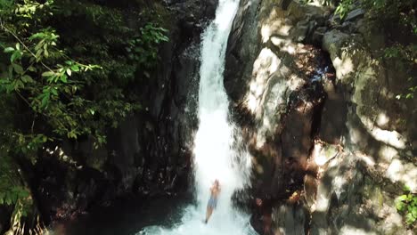 panorámica de un dron después de que alguien se deslizara por el tobogán de agua natural en la cascada de alingaling en bali, indonesia