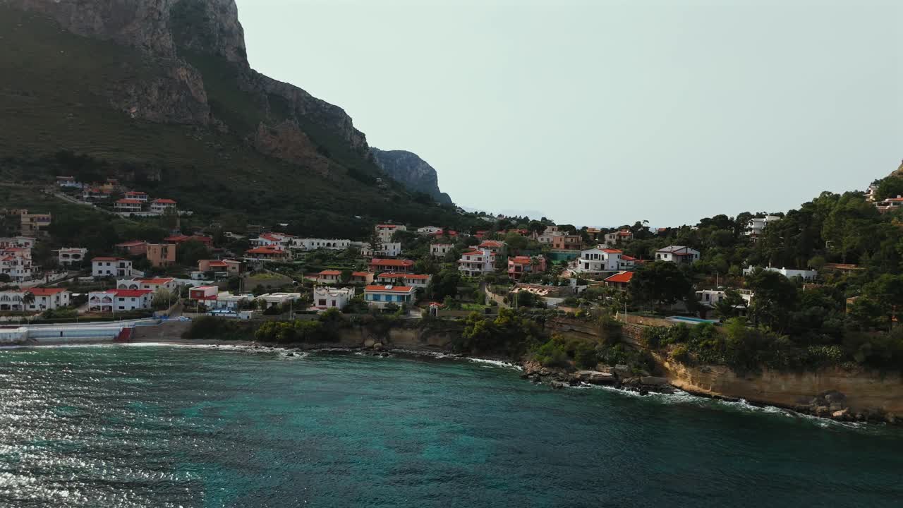 Slow motion drone footage shows detailed view of colorful coastal houses along the cliffs of Sant Elia and Capo Zafferano in northern Sicily near Palermo