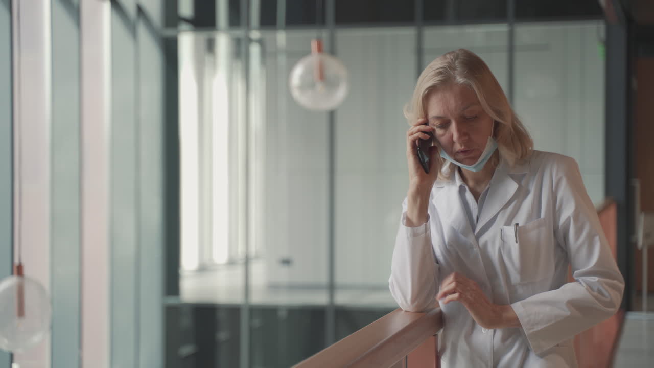 светловолосая женщина-врач средних лет разговаривает по мобильному телефону