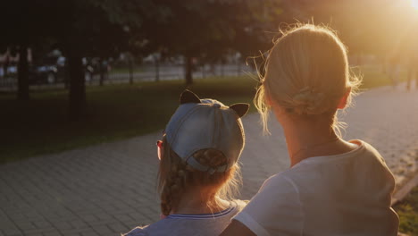 Eine-Frau-Mit-Kind-Sitzt-In-Der-Nähe-Auf-Einer-Bank-Im-Park-Passanten-Gehen-Vorbei