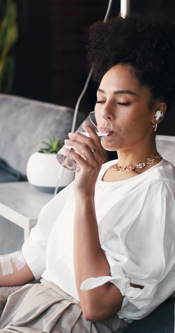 Young Woman Receiving IV Therapy While Drinking Water