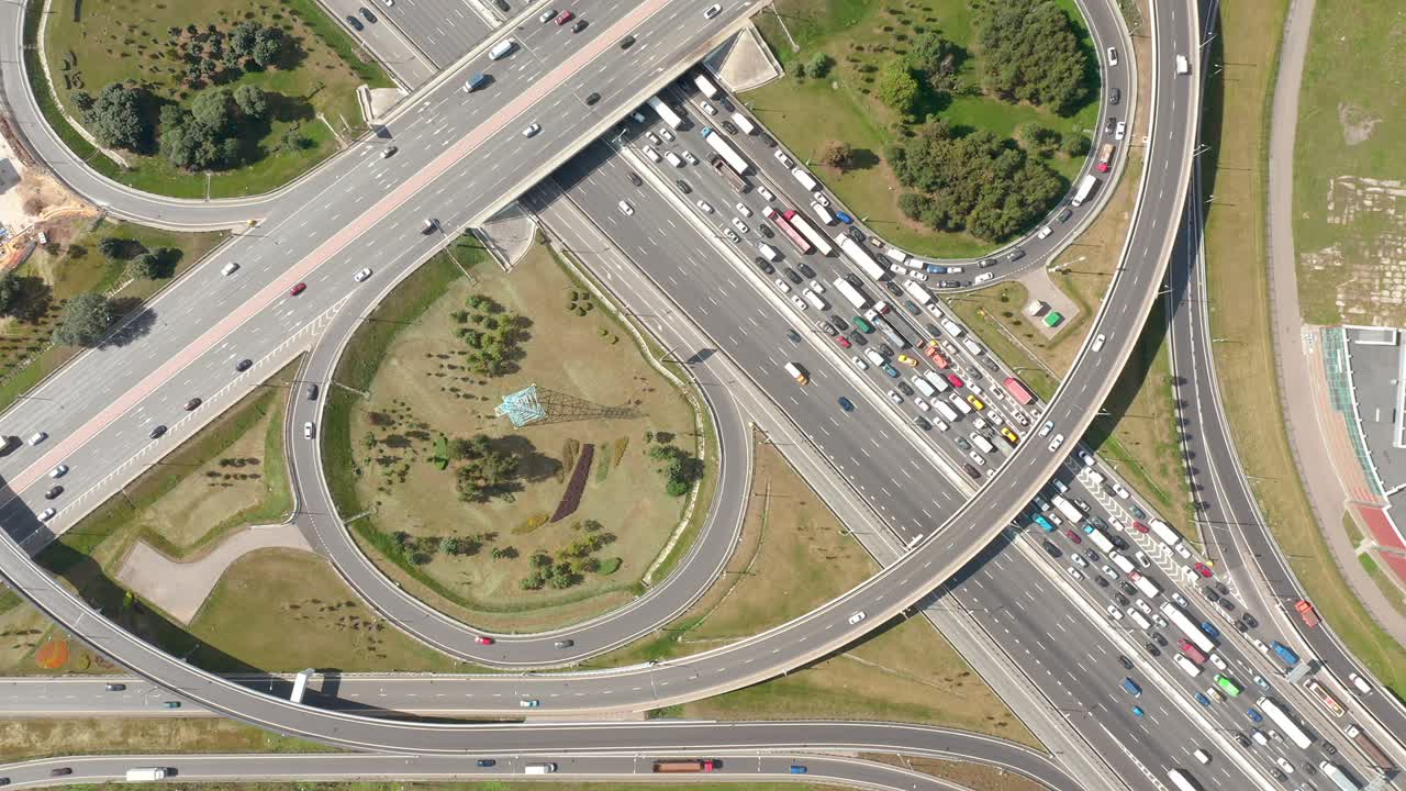 둥근 도로, 곡선 도로 및 클로버 출구와 교차로에서 드론에서 위에서 아래로 공중 전망. 대도시 개념의 교통. 여름 빛. 교차로 내부의 녹색 풀과 나무. 카메라는 정적 아래로 보입니다.