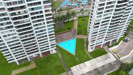 órbita aérea de una piscina de forma triangular en un condominio de edificios de forma similar, viã±a del mar, chile