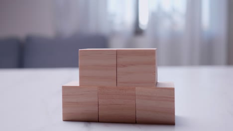 taking a close-up shot of an individual stacking wooden blocks on top of each other on a table