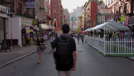 man with backpack walking on street in vibrant area of new york usa