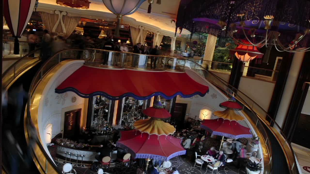 샹들리에가 위아래로 움직이는 동안 에스컬레이터를 사용하는 보행자의 저속 촬영