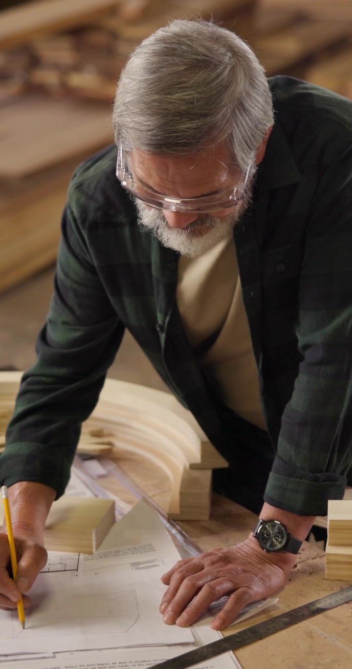 Senior Carpenter Drawing Plans in Woodworking Workshop