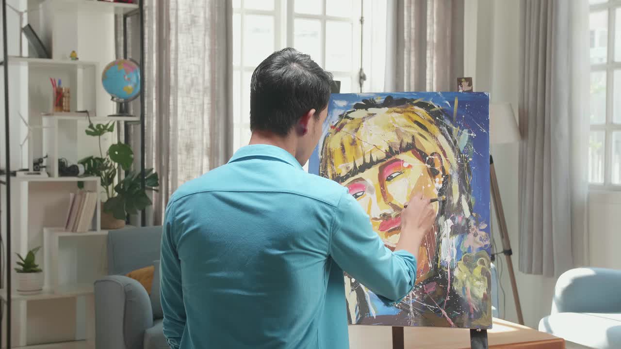 Medium Shot Hind View Of An Asian Artist Man Holding Paintbrush Mixed Colour And Painting A Girl'S Hair On The Canvas