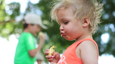 cute infant child eating an orange outside. toddler blonde boy squeezing the juice from orange fruit outside in the sunlight in 4k.mov