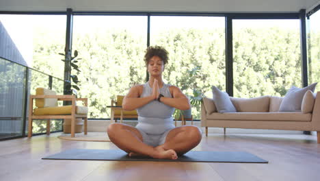 meditating on yoga mat, plus size woman practicing mindfulness in living room