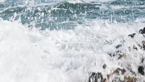 cámara lenta del poder de las olas rompiendo sobre rocas en un día soleado