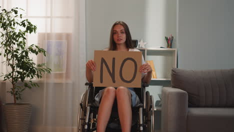 disabled woman shows poster with word no looking in camera