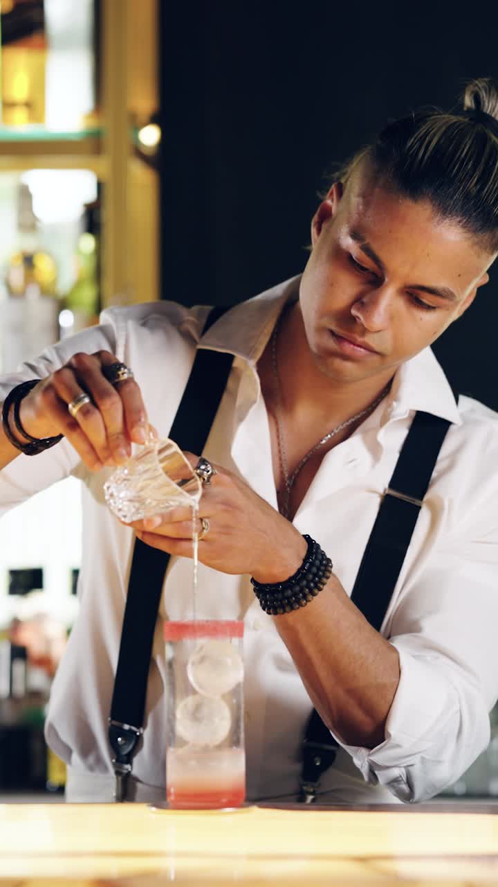 Barman che versa un cocktail in un bicchiere con sfere di ghiaccio
