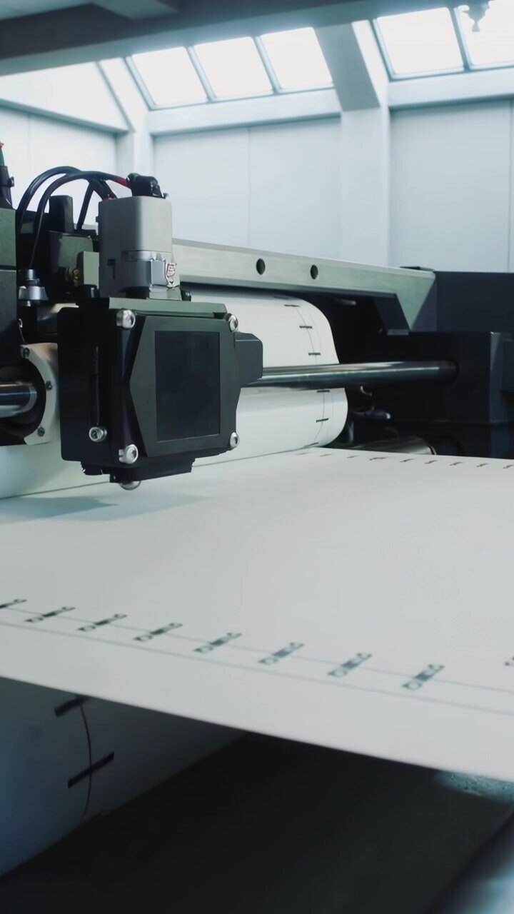 Vertical video: Feeding supply roll starting printer printing marks on wide web in plant for output