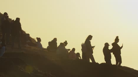 people gather on the edge of nazare beach in portugal to watch big wave surfers tackle the infamous ocean break