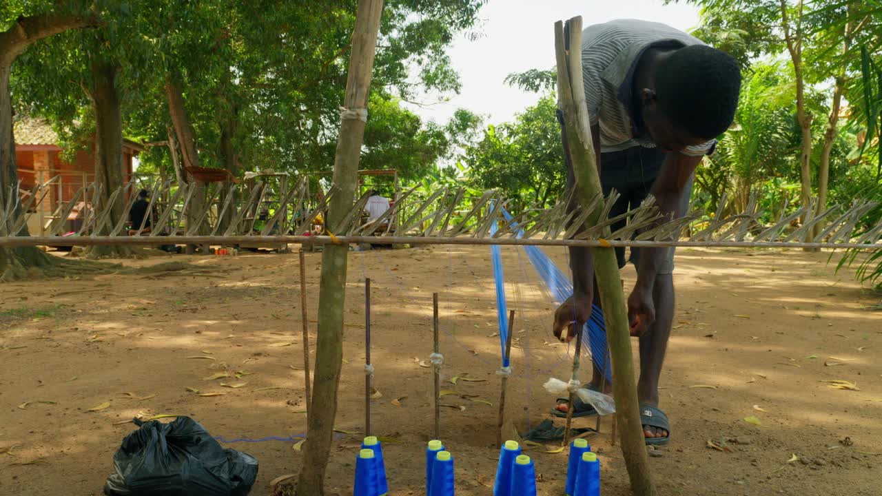 아프리카의 젊은 장인 남성이 가나에서 켄테 천을 준비하고 있습니다.