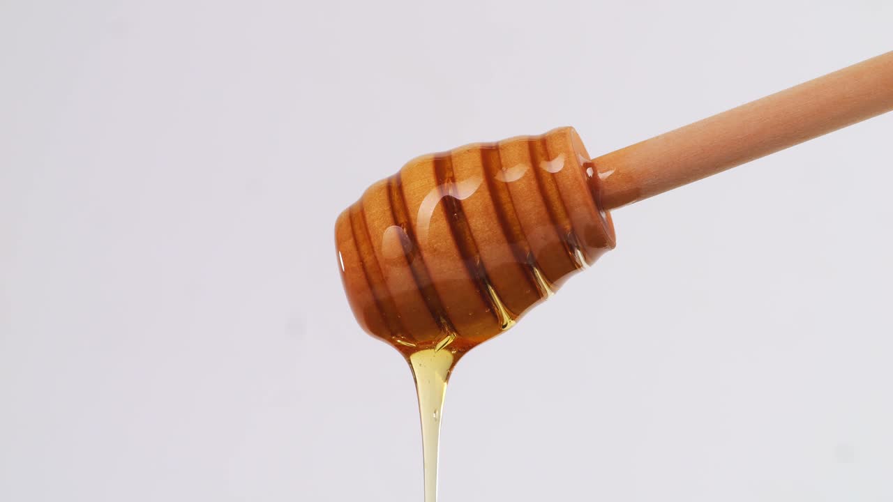 Honey Dripping From Honey Dipper On The White Background. Healthy Organic Thick Honey Closeup, Sweet Honey Dessert 4K