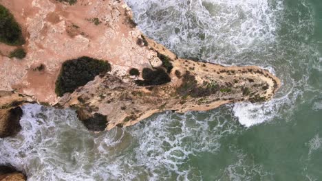 una vista de pájaro mientras asciende por encima de un afloramiento rocoso rodeado de olas fuertes