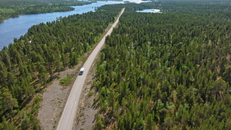 aerial view tracking a rv driving on a spruce forests of lapland, summer day