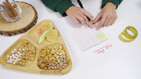 la dietista está preparando una lista de dietas y hay nueces en la mesa.