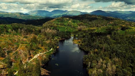 Ariel-drone-footage-of-clouds-rolling-over-mountains-and-hills-with-trees-in-Tarn-Hows-in-the-Lake-District,-Cumbria,-UK