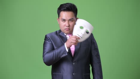 young handsome overweight asian businessman against green background