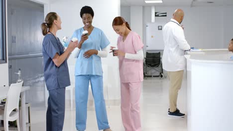 diverse female doctors talking and drinking coffee at hospital, slow motion