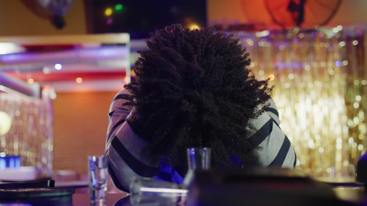 Video of drunk african american man sitting at the bar with head down after drinking too much