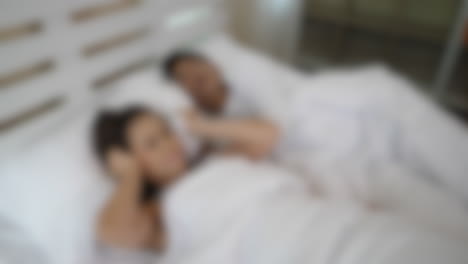 Blurred-shot-of-wife-bothered-by-loud-snoring-of-her-husband-in-bed,-sleepless-nights-and-annoyed-in-marriage-concept