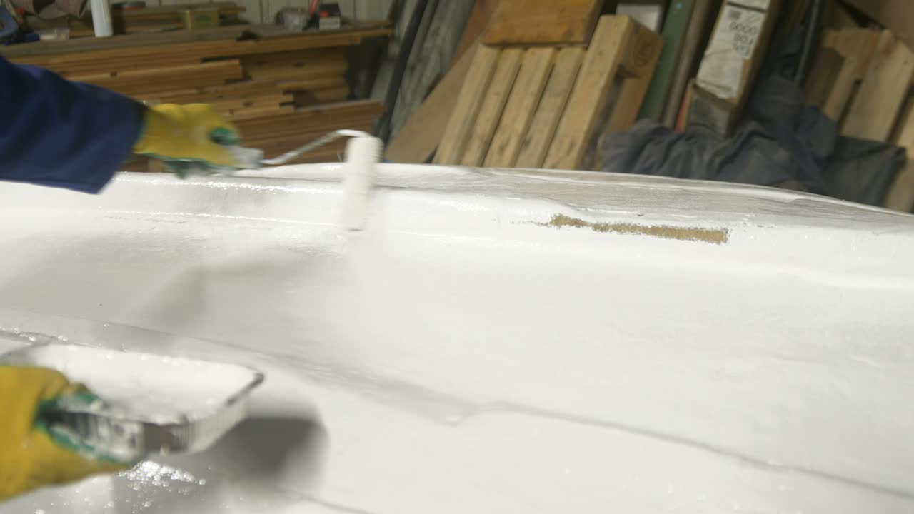 Verniciare di bianco lo scafo di una barca in vetroresina usando un rullo