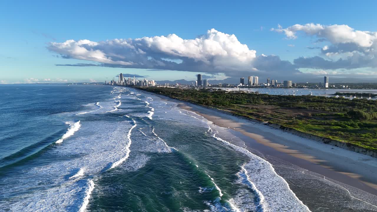 Drone captures sweeping views of Gold Coast's coastline, waves, and city skyline under clear blue skies