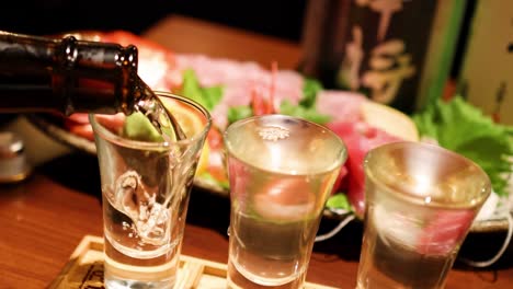 vertiendo sake en vasos sobre platos de sushi