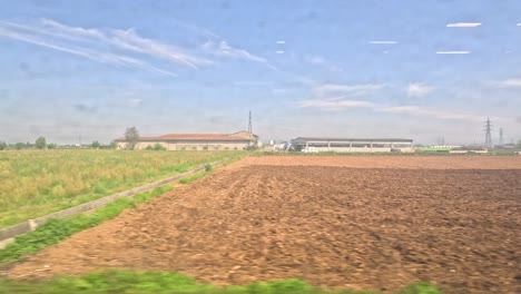 passing fields and buildings near milan, italy